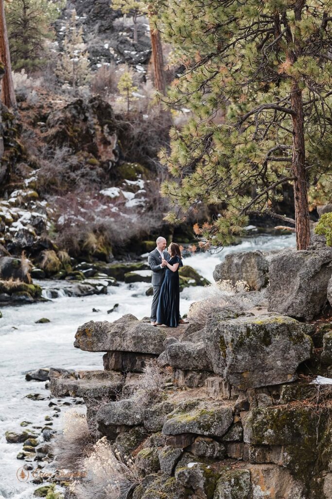 A couple embraces near a river in Oregon.