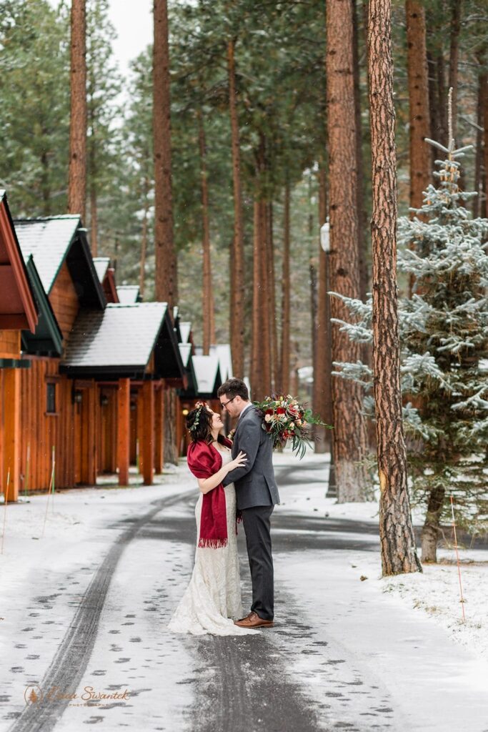 A couple embraces near cabins during their Winter Oregon elopement.