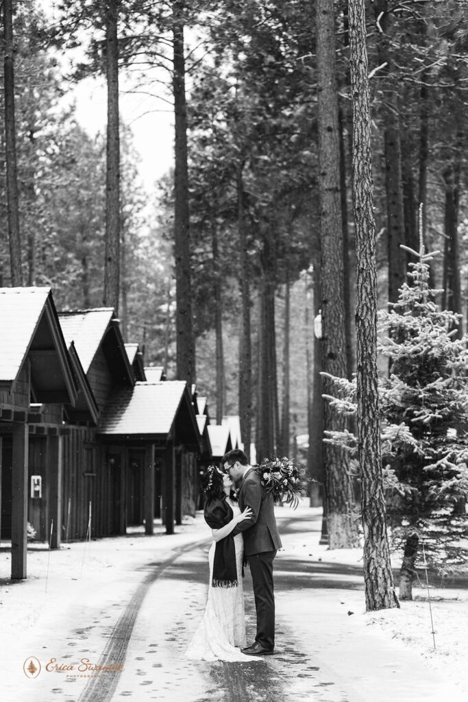 A couple stands near cabins for their wedding in Oregon.