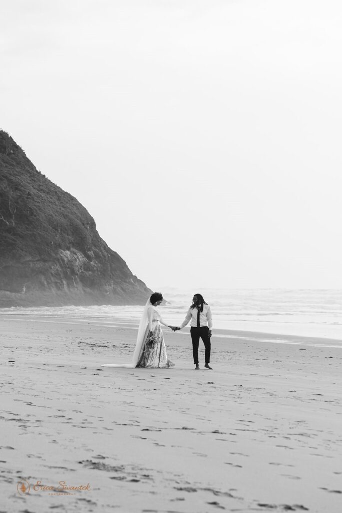 A couple holds hands on a coastal beach in Oregon for their wedding.