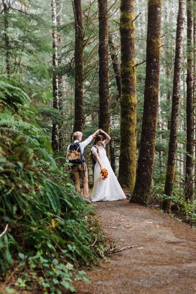 A bride twirls with her partner in the forest.