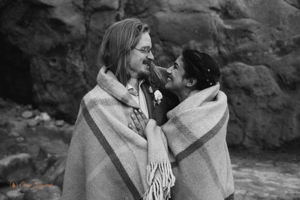 elopement couple snuggling under a blanket at oregon coast