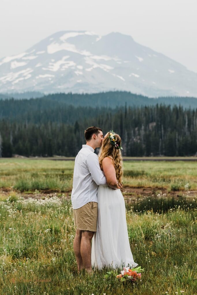 A couple kisses in a grassy meadow in Deschutes National Forest.