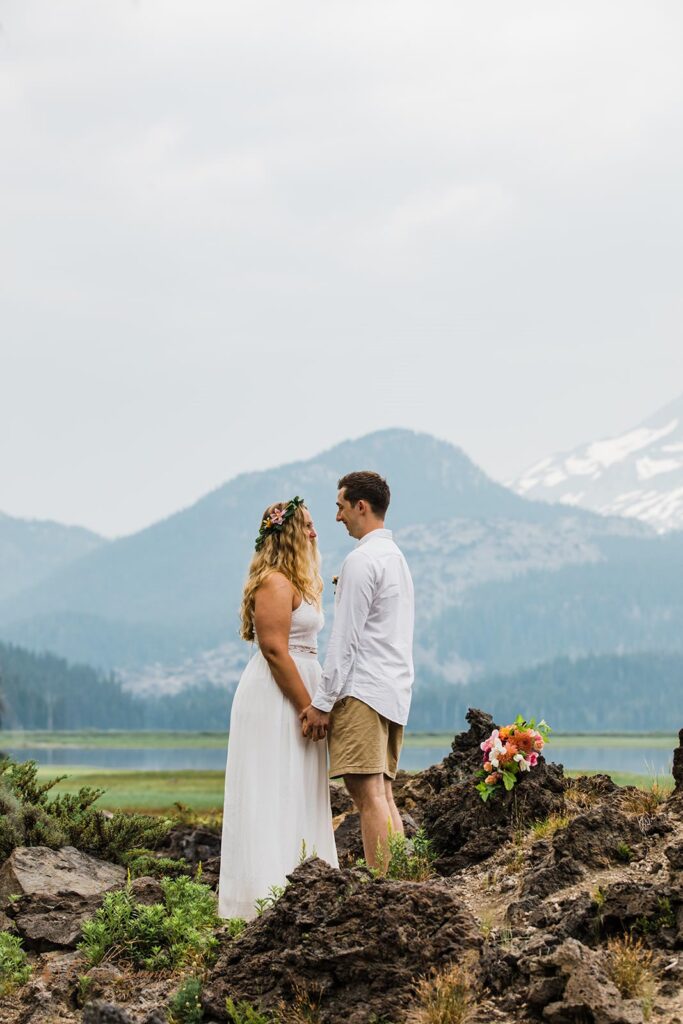 A newlywed couple holds hands near the Cascades.