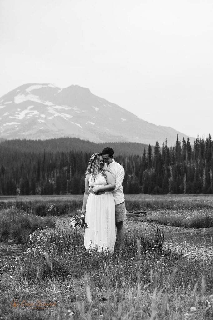 A couple embraces near the Cascades in an Oregon meadow.