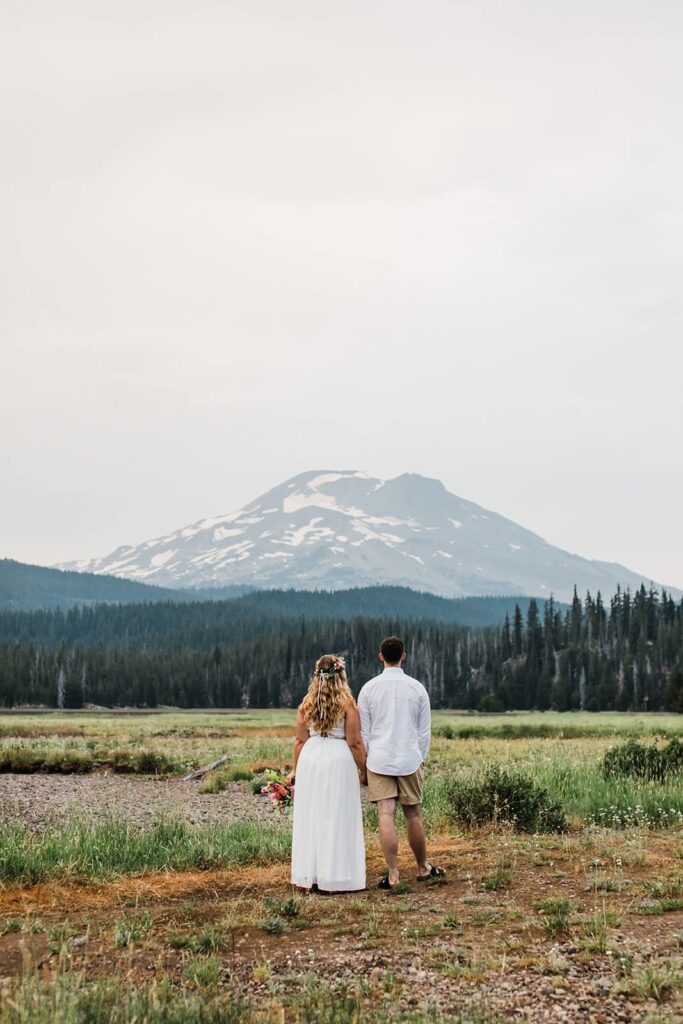 A couple on an adventure elopement admires a mountain peak.