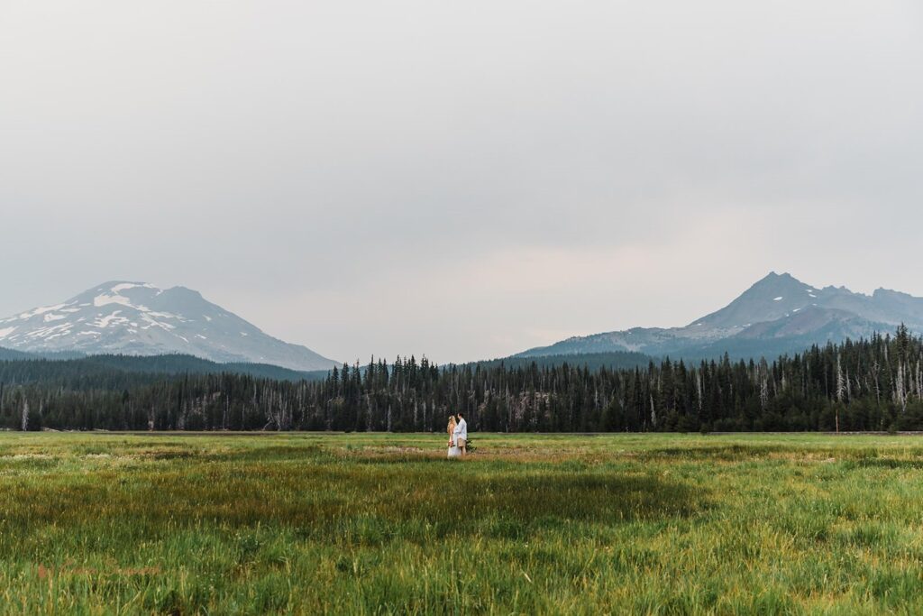 A landscape portrait of a couple in a green meadow in Central Oregon.