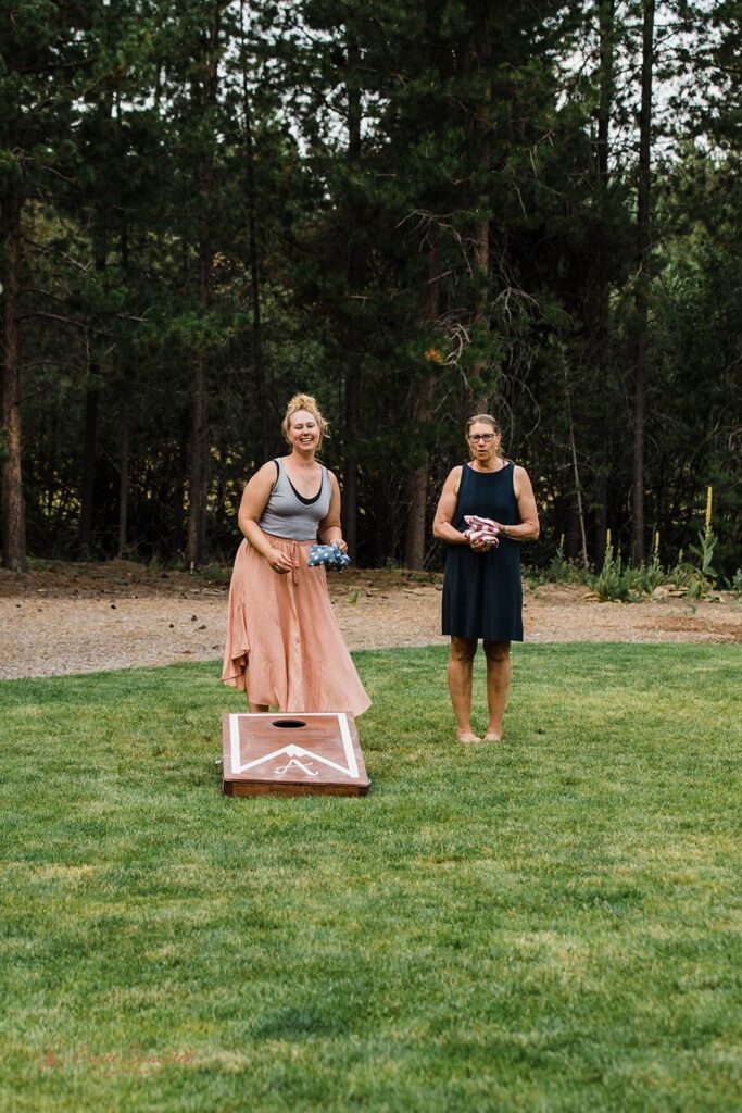 A woman plays corn hole with her family.