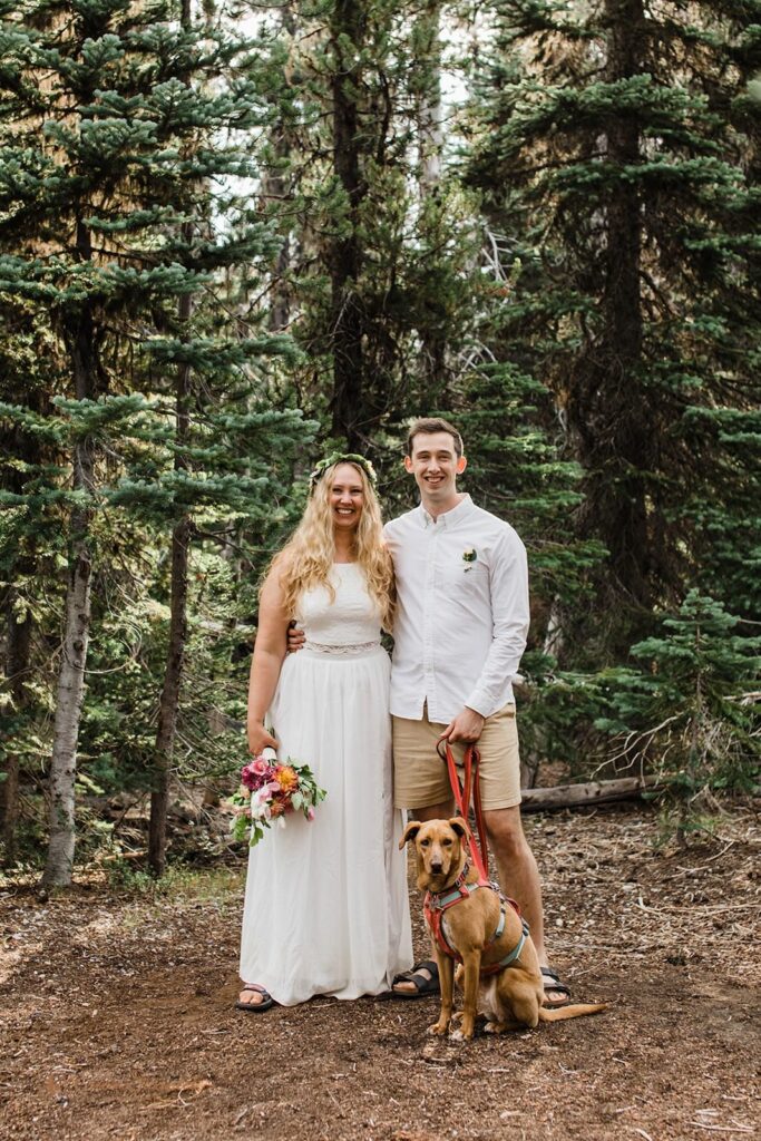 A couple stands in an Oregon forest during their adventure elopement with a dog.