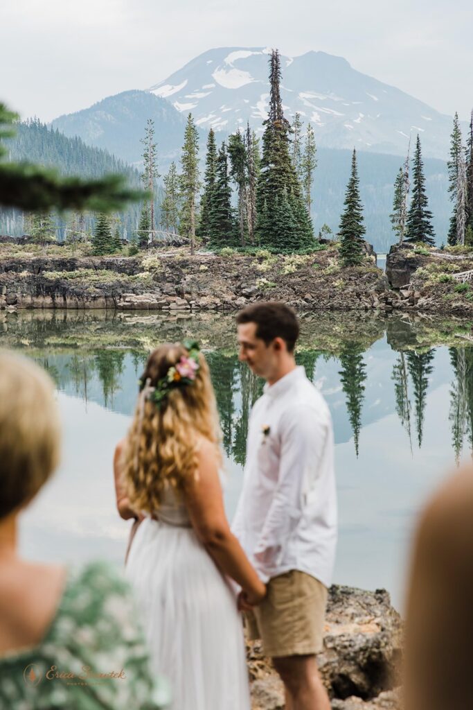 A couple stands near an alpine lake for their elopement in Oregon.