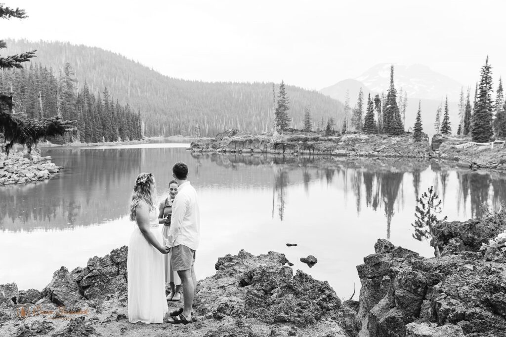 A couple holds hands during their intimate wedding ceremony at Sparks Lake near Bend, Oregon.