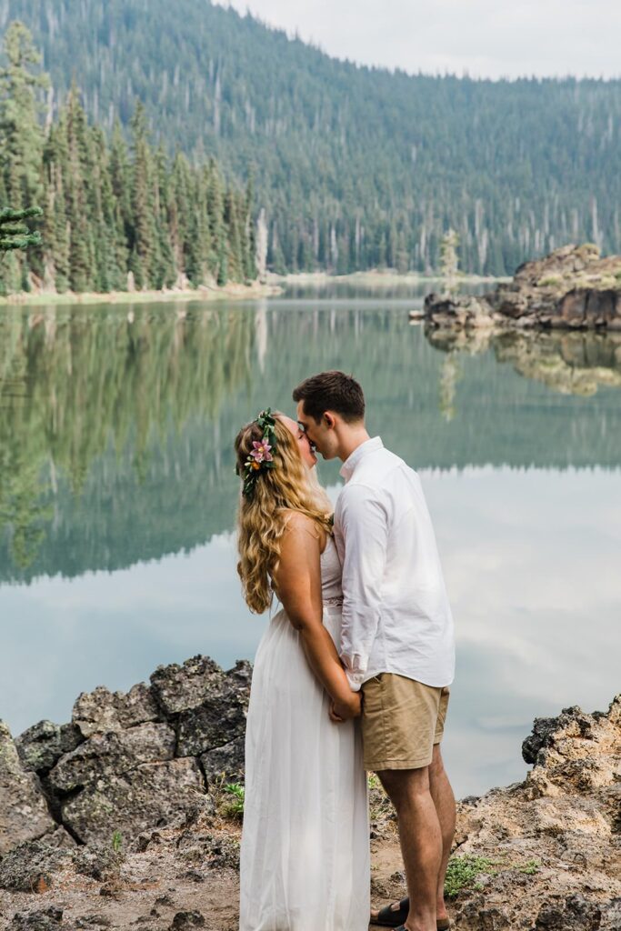 A couple shares a kiss near an alpine lake in Oregon.