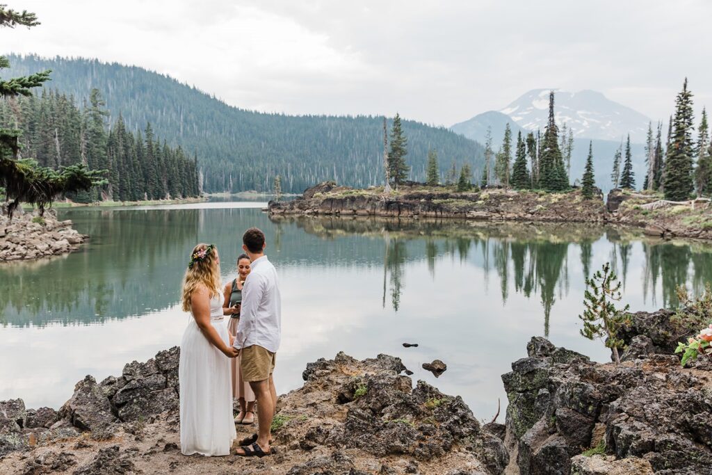 A couple stands near Sparks Lake during their intimate wedding ceremony.