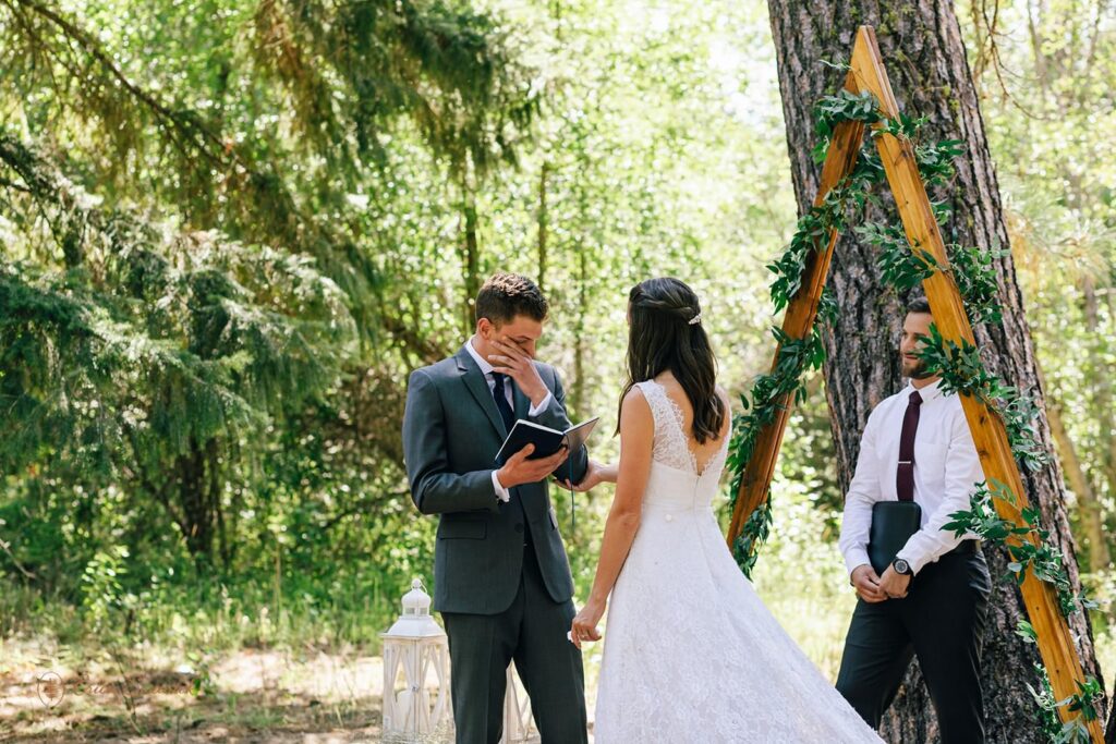 A groom wipes away tears while reading vows during an outdoor intimate wedding in Washington.