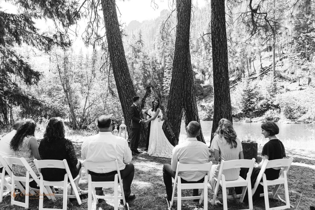 A newlywed couple and their guests during an outdoor elopement by a river.