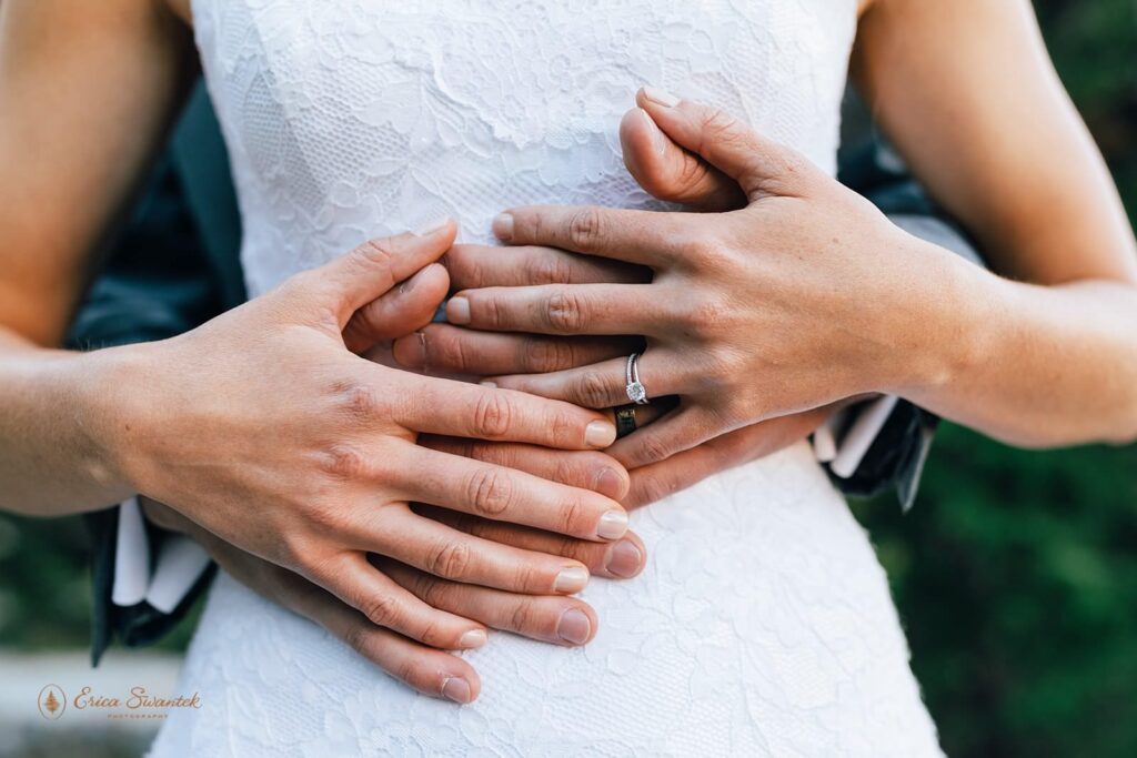 A couple's hands display their wedding rings in an embrace.