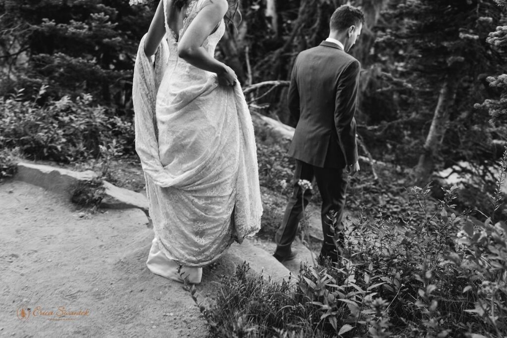 A bride follows her soon-to-be husband down a hiking trail in Mt. Rainier National Park.