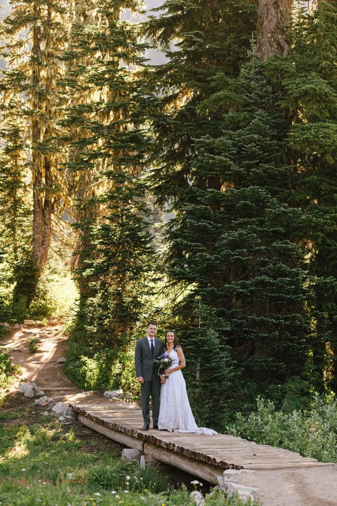 A couple smiles for wedding portraits while on a bridge in Mt. Rainier National Park.