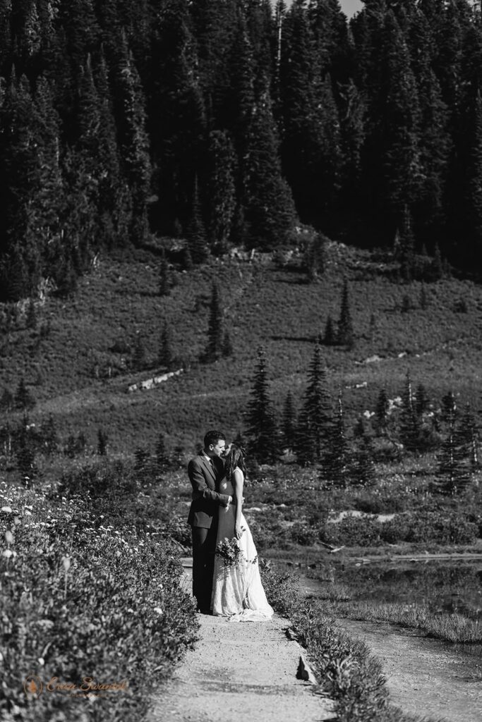 A couple kisses along a hiking trail in Washington during their Mt. Rainier elopement.
