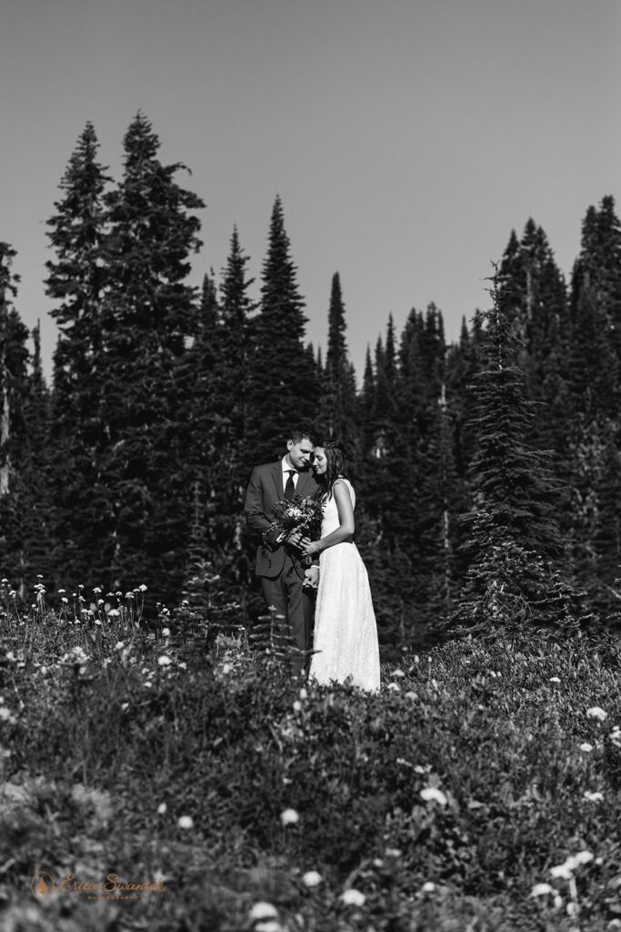 A couple in wedding attire embraces while a groom holds a floral bouquet. 