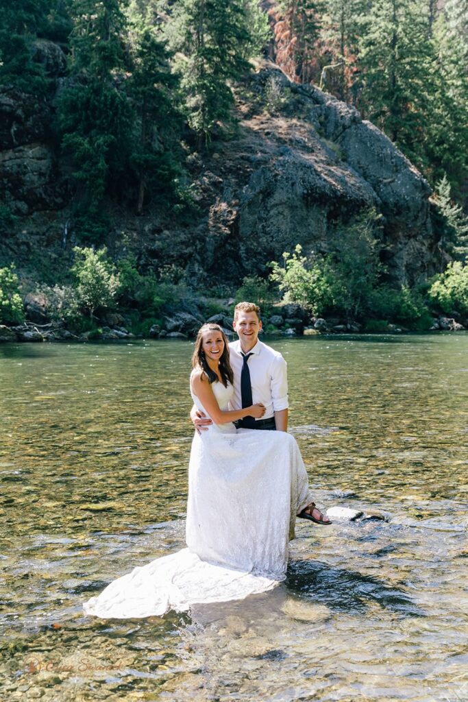 A couple in elopement attire stands in Naches River.