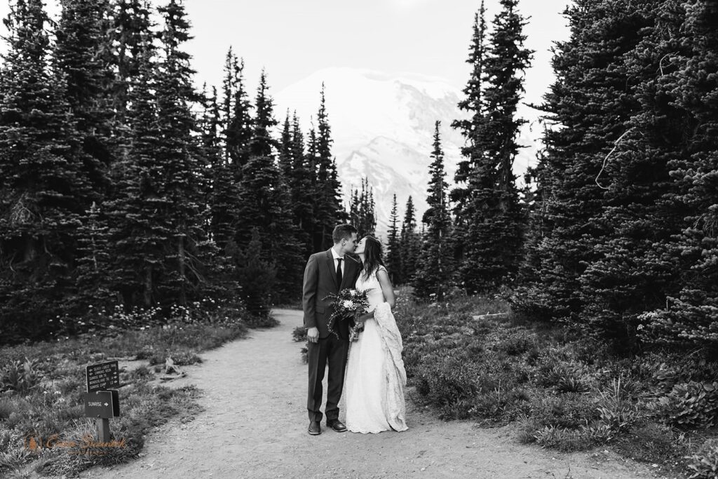 An adventure elopement couple shares a kiss while on a hiking trail in Mt. Rainier National Park. 