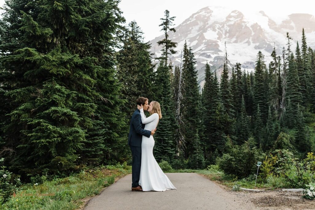 A couple kisses in Mt. Rainier National Park on a trail.