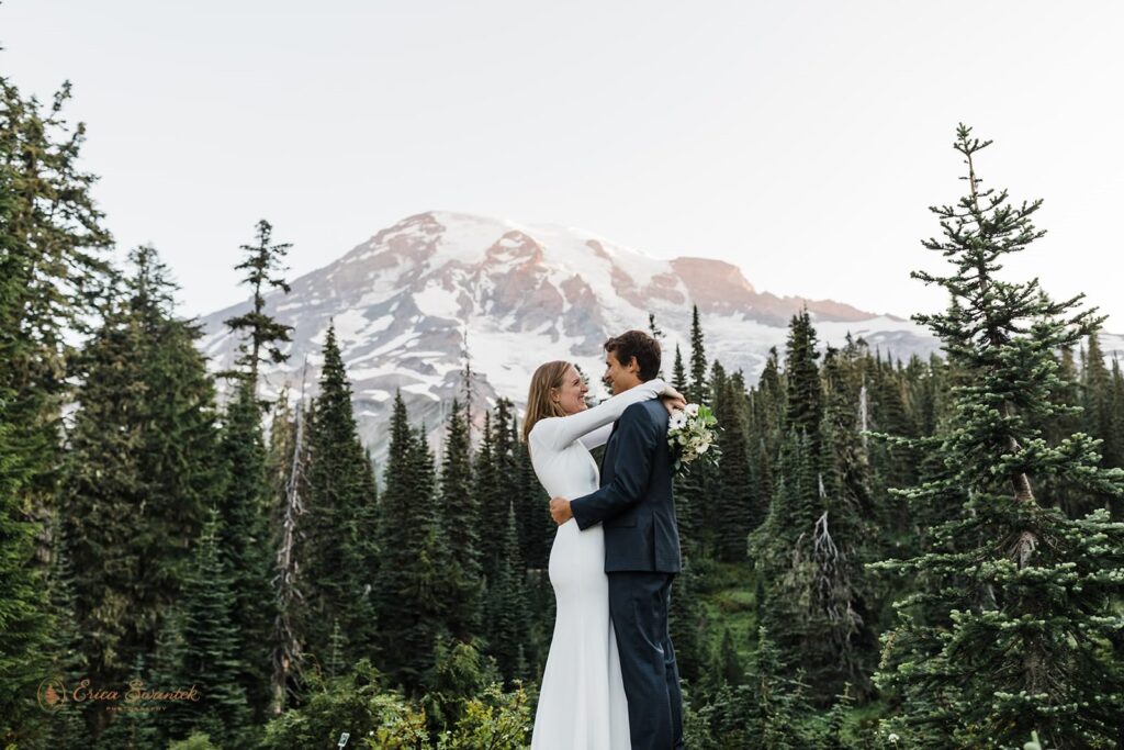 An adventure elopement couple embraces in front of Mt. Rainier. 