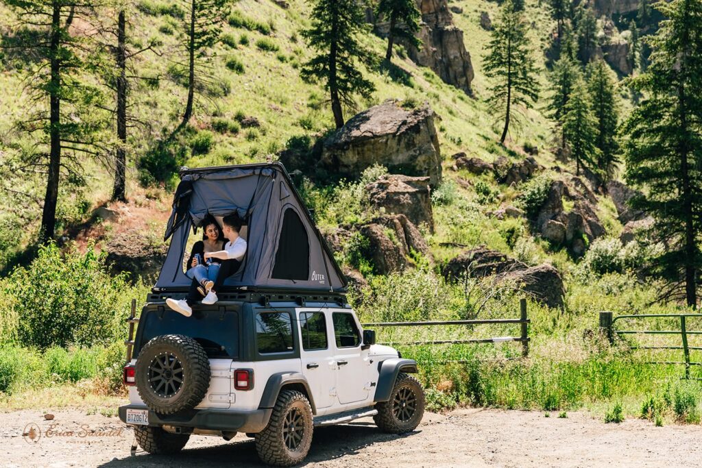 A newly engaged couple sits on a Jeep rooftop in Washington.