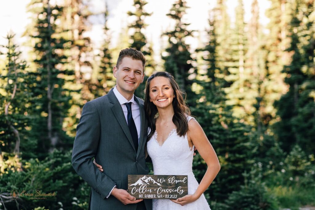 A couple holds a we eloped in Mt. Rainier wooden sign. 