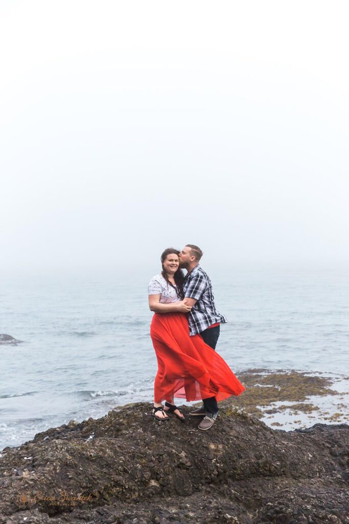 A man kisses a woman on the forehead during their engagement photos on the Washington Coast.