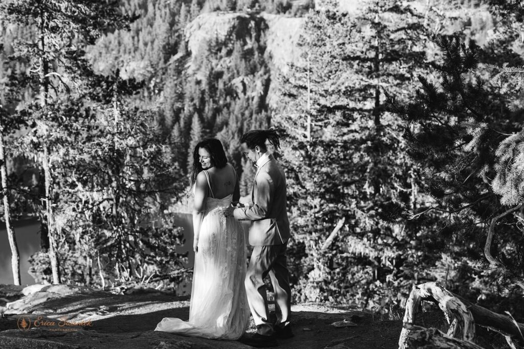 A man helps his bride put on her wedding dress along a Washington State hiking trail.
