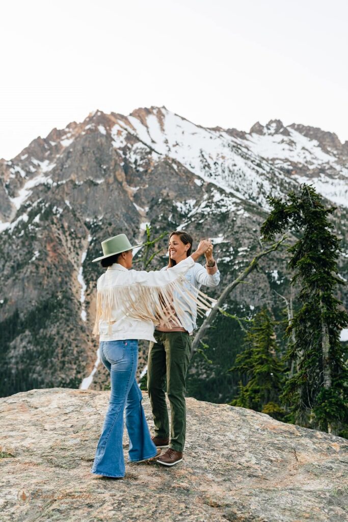 A couple dances on a rocky overlook in the mountains of Washington State during their adventure session.