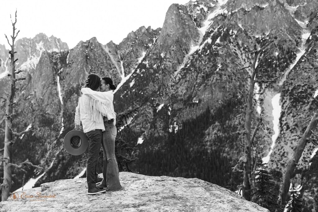A couple embraces on an overlook during an adventure session in the mountains of Washington State.