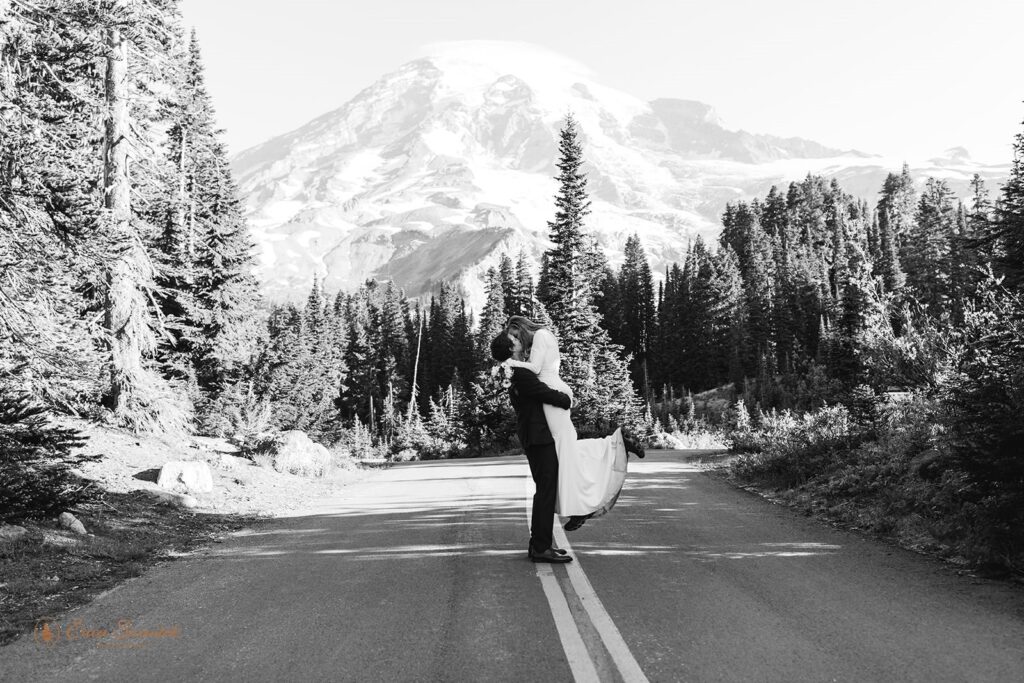 A couple kisses on a remote road in Mt. Rainier National Park. 