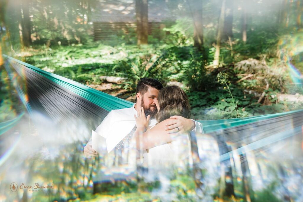 A couple embraces in a hammock while exchanging love notes in a Washington forest.