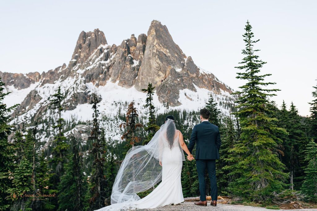 A couple holds hands while admiring a mountain peak in Washington.