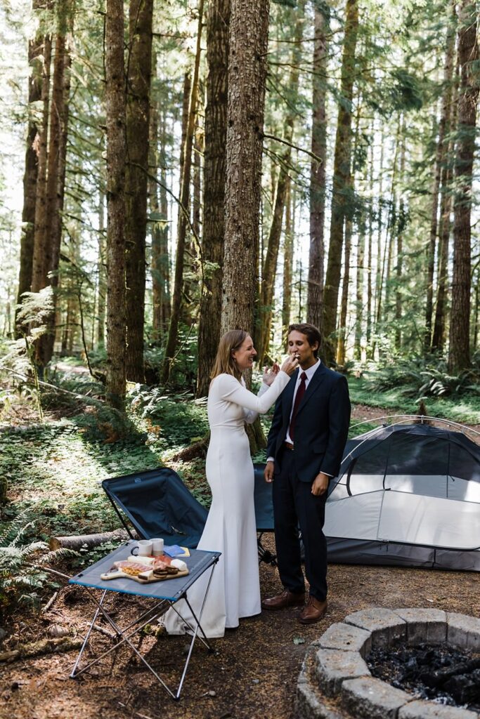 A couple shares food during their campsite elopement picnic.