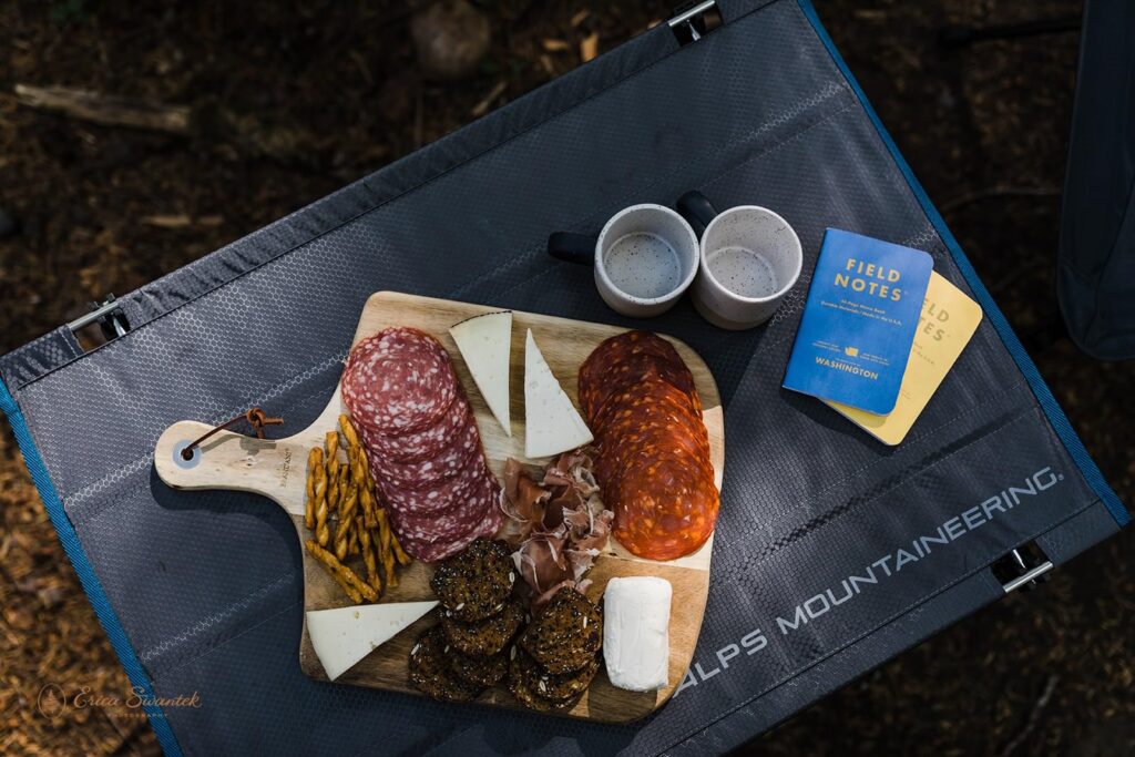 A couple shares a charcuterie board during their elopement picnic. 