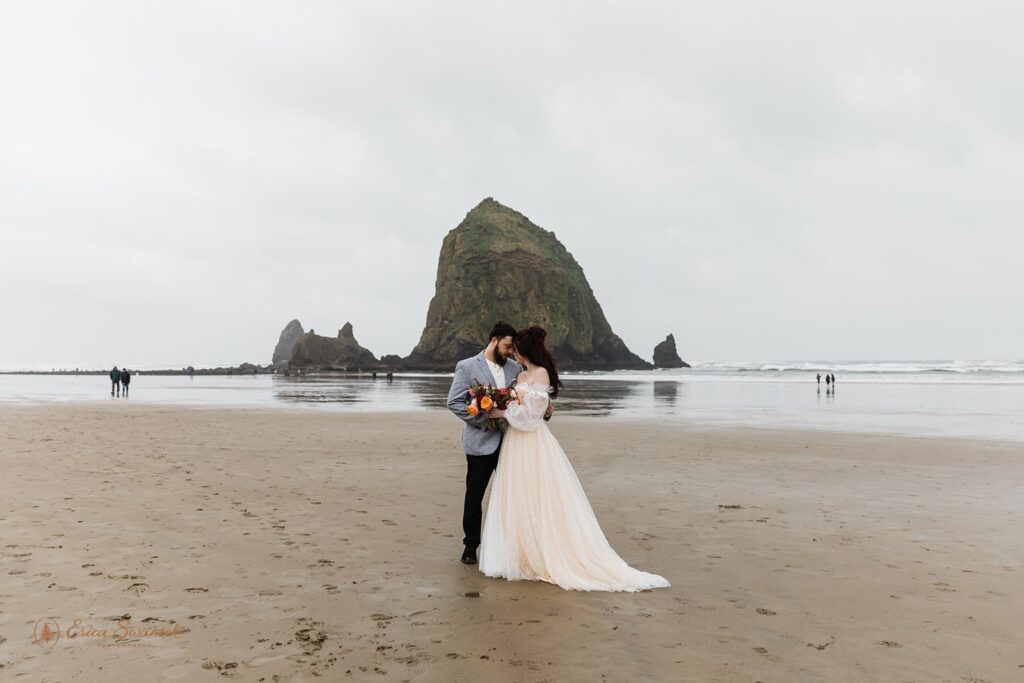 A couple poses for wedding portraits on Cannon Beach during their Oregon Coast intimate elopement.