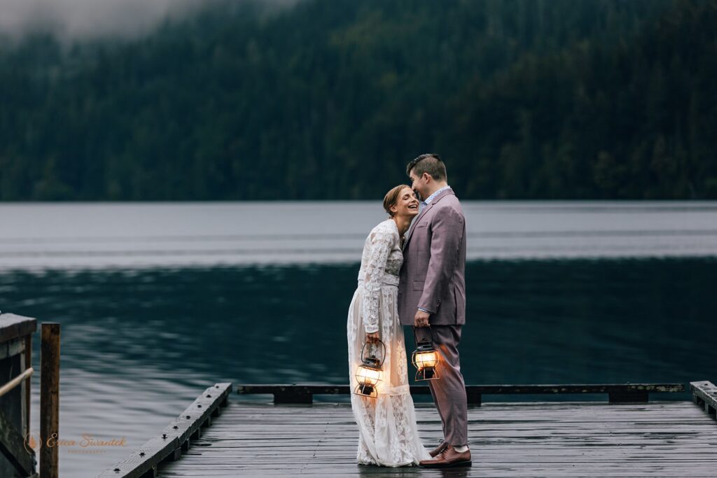 bride and groom holding lanterns on a wooden deck during their olympic national park elopement