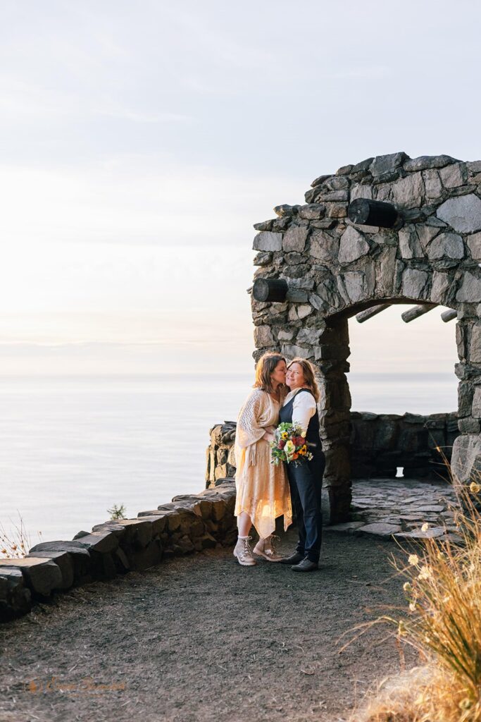 A couple shares a kiss at a pavillion overlooking the Pacific Ocean at Sunset at Cape Perpetua. 