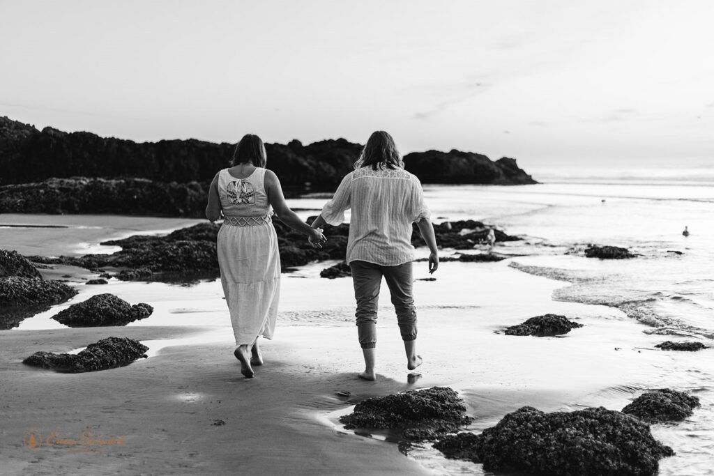 A couple walks along the rocky Oregon Coastline during their September elopement in the Pacific Northwest. 