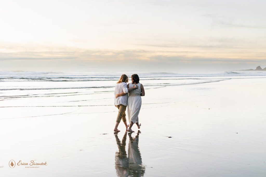 A couple walks while holding one another along Neptune Beach in Oregon at Sunset.