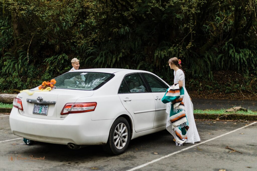 A couple gets ready near their car before a forest elopement in Oregon. 