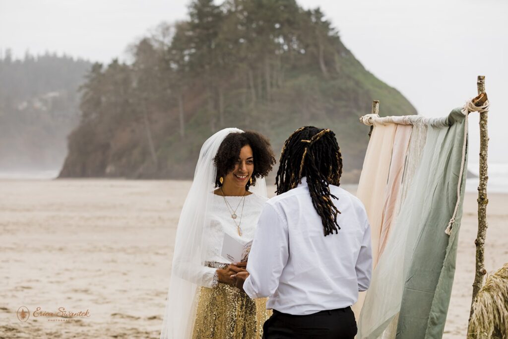 A couple says intimate vows during a boho beach celebration near Proposal Rock. 