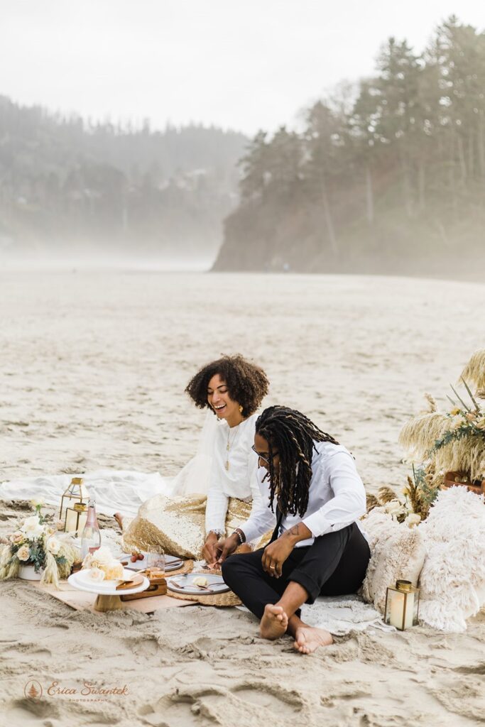 A couple sits on a picnic blanket during their Proposal Rock elopement.