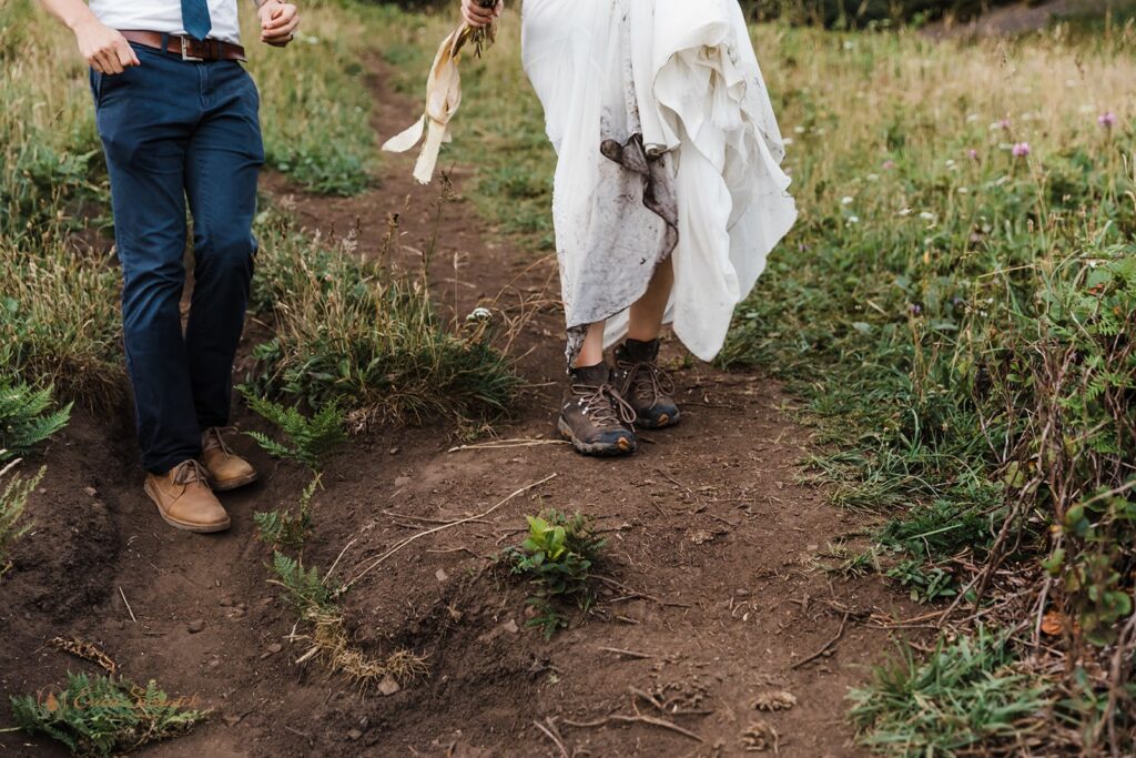 A couple shoes are shown walking along a dirt trail during a hiking elopement .