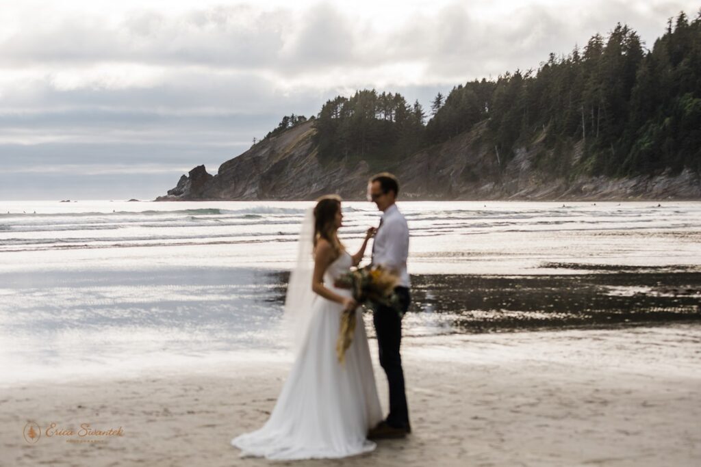 A bride adjusts her groom's tie on Short Sand Beach during their coastal elopement.