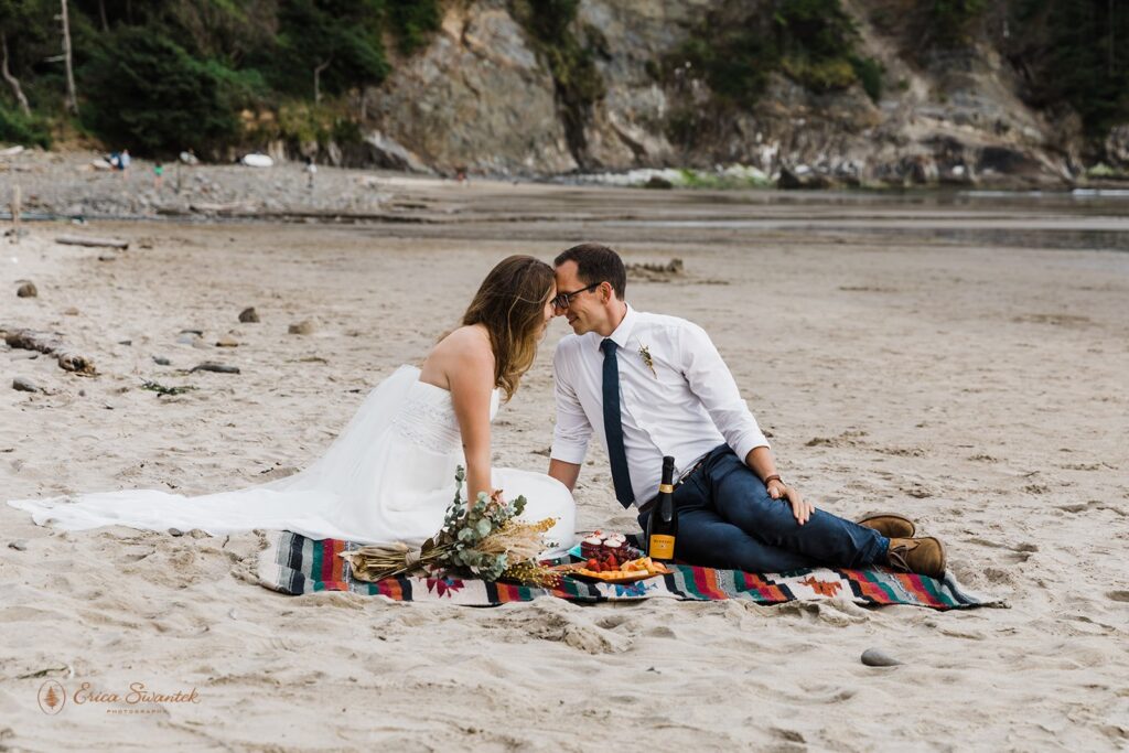 A couple shares a beach picnic during their Oregon Coast elopement just before Sunset.